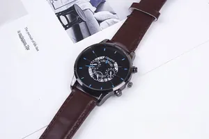 Detail of quartz watch with black dial and dark brown leather strap on magazine