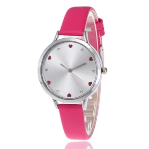 Macro detail of silver watch dial with red heart hour markers and rose pink leather strap
