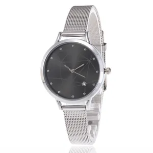 Detail of silver mesh band watch with dark grey geometric textured dial and star accent