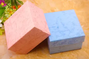 Detail view of pink and light blue square gift boxes with marble texture and lid