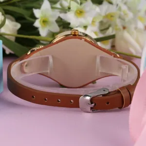 Détail du bracelet en cuir marron et du boîtier de montre à quartz en or rose poli