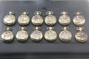 Dettaglio di dodici orologi da taschino zodiaco in bronzo su sfondo di pelle nera