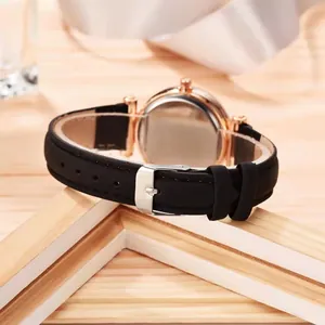 Close-up of women's quartz watch with black leather strap and rose gold case back