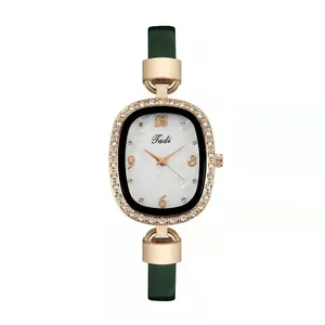 Detail of rose gold watch with marble dial, rhinestone bezel, and dark green leather strap