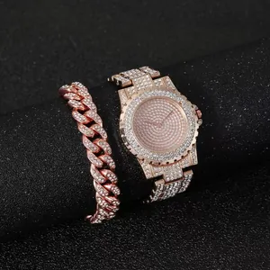 Close-up of iced-out rose gold watch and Cuban link bracelet set on a black display