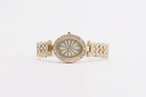 Detailed macro view of the gold-tone oval watch face with crystal encrusting and daisy pattern