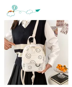 White corduroy backpack with smiley face pattern shown on a school style outfit