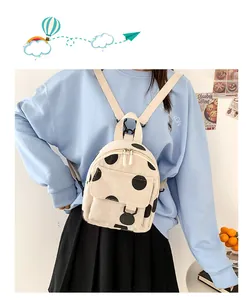 Detail of a beige corduroy mini backpack with black polka dots on a model back