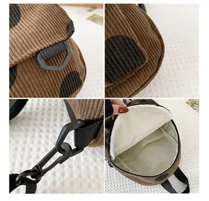 Detail view of brown corduroy backpack showing black polka dots and durable plastic hardware