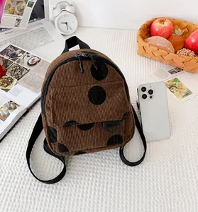 Mini corduroy polka dot backpack shown next to a phone for size comparison