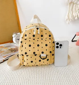 Kleiner gelber Cord-Rucksack mit Blumenmuster im Größenvergleich zu einem Smartphone