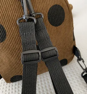 Detail of adjustable black nylon shoulder straps on a brown polka dot corduroy backpack
