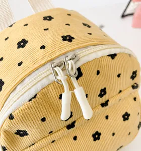 Nahaufnahme der glatten Metallreißverschlüsse und Blumenmuster auf dem Kordrucksack