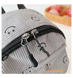 Detail of smooth double zipper and smiley face print on grey corduroy backpack