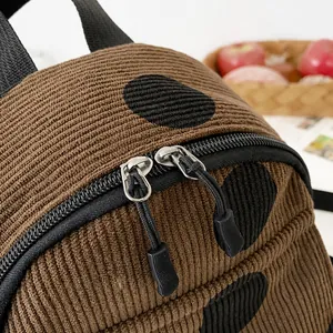 Detail of smooth double zippers on brown corduroy backpack with black polka dot pattern