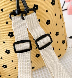 Details verstellbarer Schultergurte am gelben Cord-Rucksack mit Blumenmuster und Schnalle