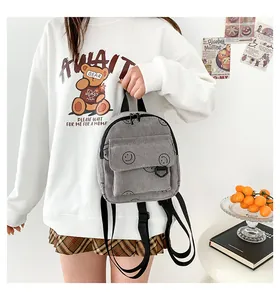 Detail of grey corduroy backpack with smiley face prints and a flap front pocket