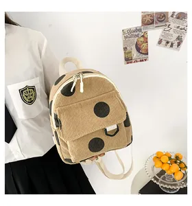 Detail of beige corduroy mini backpack with black polka dots and nylon shoulder strap