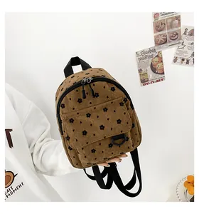 Close-up of brown corduroy mini backpack with floral print and buckle flap pocket