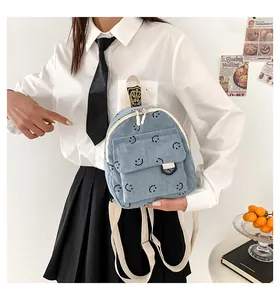 Close-up of light blue corduroy mini backpack with black smiley face prints on a model