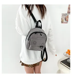 Close-up of grey corduroy mini backpack with black smiley face and adjustable straps