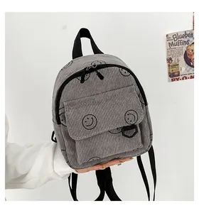 Detail of grey corduroy backpack showing smiley pattern and texture with zipper pocket