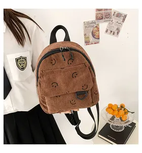 Close-up of brown corduroy backpack with smiling face patterns and black handles