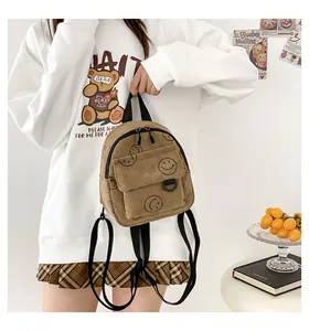 Detail of khaki corduroy backpack featuring a black smiley face print and front flap pocket