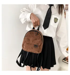 Close-up of brown corduroy mini backpack featuring a black smiley face print and zipper