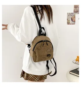 Detail of khaki corduroy mini backpack featuring black smiley faces and dual zippers