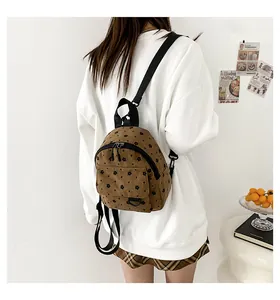 Detail of corduroy texture and floral pattern on the brown small backpack worn by a model
