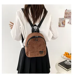 Brown corduroy mini backpack with smiley face pattern shown on a female model