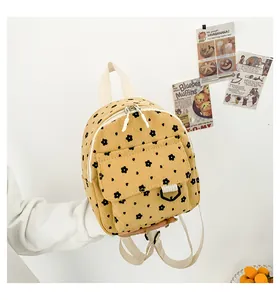 Detailed close-up of corduroy mini backpack with floral pattern held by a hand