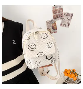 Detail of cream corduroy mini backpack with black smiley face pattern and canvas straps