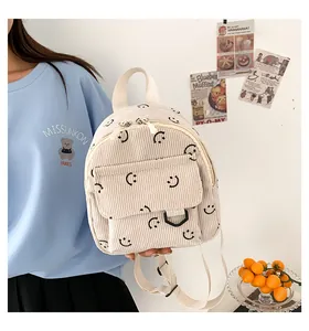 Close-up of cream corduroy mini backpack with black smiley face pattern and front pocket