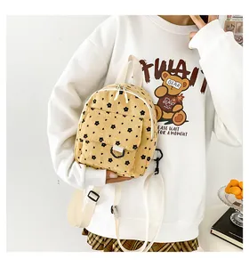 Detail of yellow corduroy mini backpack with floral pattern and front flap pocket