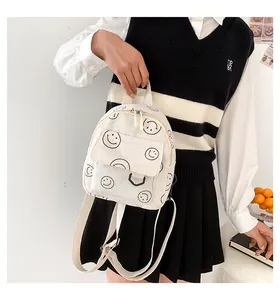 Close-up of a cream corduroy mini backpack with black smiley face prints and top handle