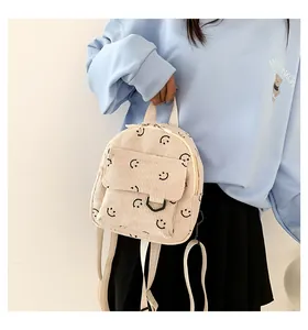 Detail of a beige corduroy mini backpack with cute black smiley face patterns