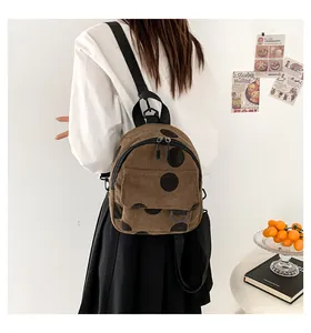 Brown corduroy polka dot mini backpack with adjustable straps in a cozy lifestyle setting