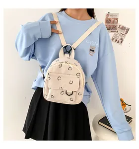 Detail of a creamy white corduroy mini backpack featuring an all-over black smiley face pattern
