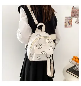 Mini corduroy backpack with smiley face print worn by model in a cozy lifestyle setting