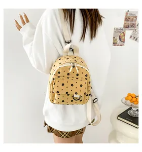 Detail of yellow corduroy mini backpack featuring black floral print and adjustable straps