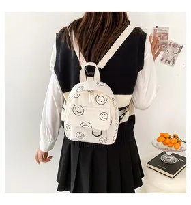 Lifestyle shot of white corduroy mini backpack with black smiley face prints on a model