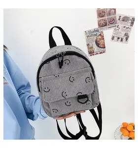 Detailed macro view of gray corduroy mini backpack fabric with embroidered smiley face patterns