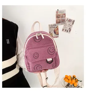 Detailed view of a purple corduroy mini backpack featuring a black smiley face pattern