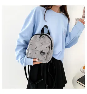 Detail of grey corduroy backpack with smiley face pattern worn by a model in a casual style