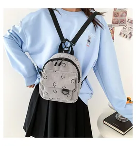 Detailed view of grey corduroy mini backpack featuring smiley face prints and nylon straps