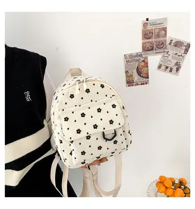 Detail of white corduroy mini backpack with black floral pattern worn by a model