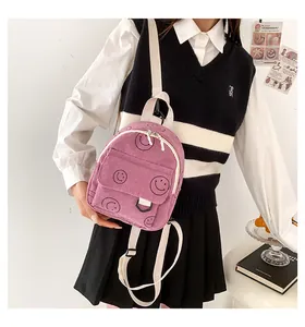 Detail of purple corduroy backpack with black smiley patterns and cream shoulder straps
