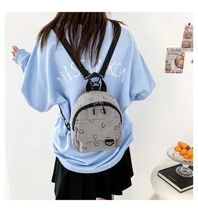 Detail of grey corduroy backpack with black smiley patterns worn by model in casual setting